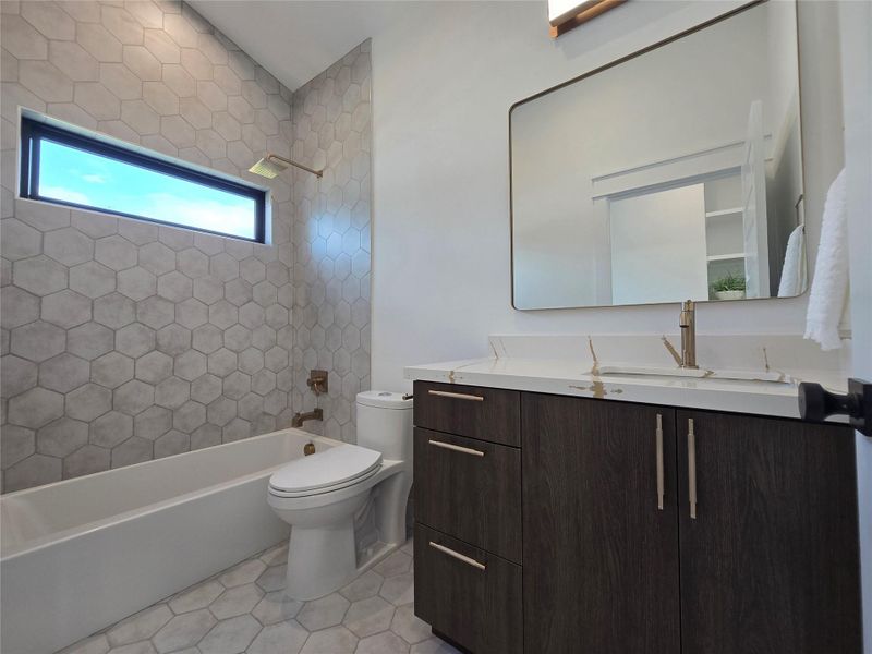 Full bathroom featuring tile patterned floors, shower / bath combination, vanity, and toilet Full bathroom featuring tile patterned floors, shower / bath combination, vanity, and toilet