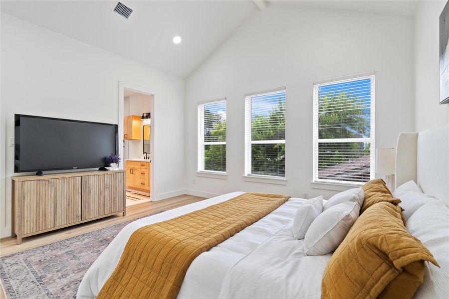 A seamless flow into the ensuite bath adds convenience while maintaining the open and airy feel of this thoughtfully designed oasis.