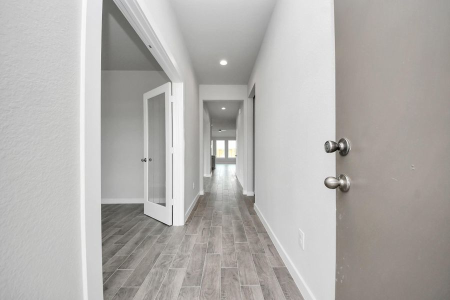 Greeted by a elegant glass front door, the entrance beckons with high ceilings, adorned with elegant wood-look tile flooring and oversized baseboards. Sample photo of completed home with similar floor plan. Actual colors and selections may vary.