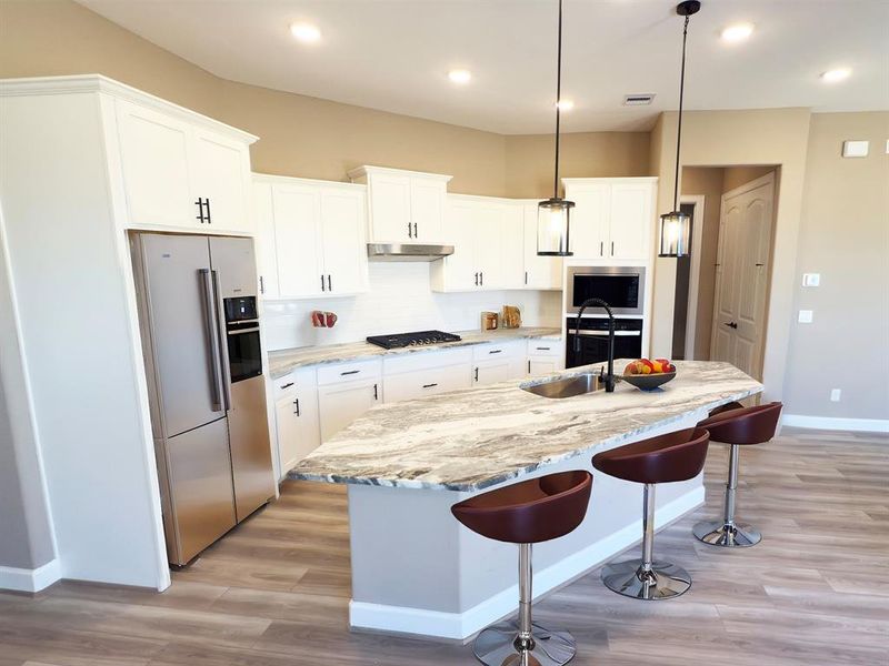 The Portico A’s kitchen at Winfrey Estates is a chef’s dream, featuring sleek stainless steel appliances, custom cabinetry, and expansive countertops—blending modern luxury with effortless functionality for an unparalleled culinary experience. *Image depicts home as-is.