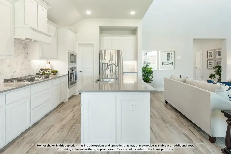 Open kitchen with white cabinets, center island, stainless steel appliances, and light wood-look tile floors open to living area. Open kitchen with white cabinets, center island, stainless steel appliances, and light wood-look tile floors open to living area.