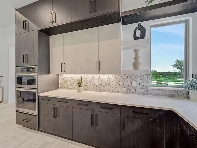 Kitchen featuring stainless steel double oven, backsplash, light stone counters, dark brown cabinetry, and light wood-type flooring