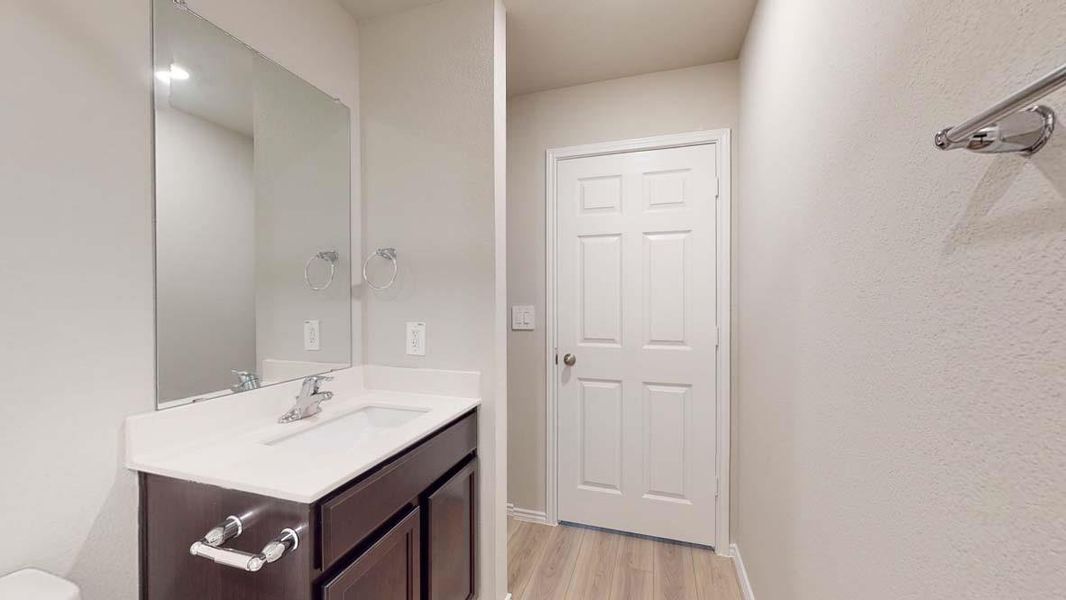 Bathroom vanity featuring dark wood-finish cabinetry, a white countertop, and an integrated sink with a chrome faucet