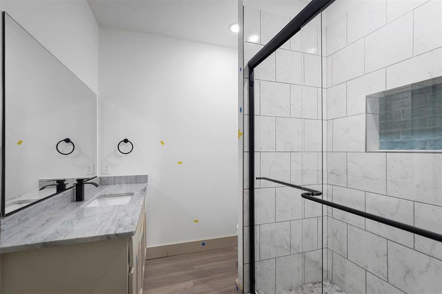 Bathroom featuring vanity, wood finished floors, baseboards, and a stall shower