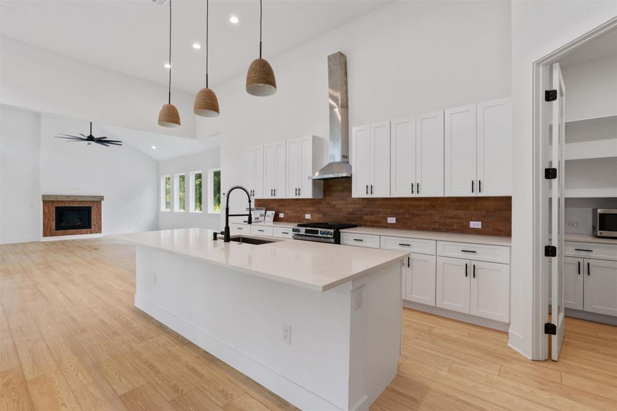 A well-appointed kitchen features a large central island, crisp white cabinetry, and light wood flooring, creating an inviting space.