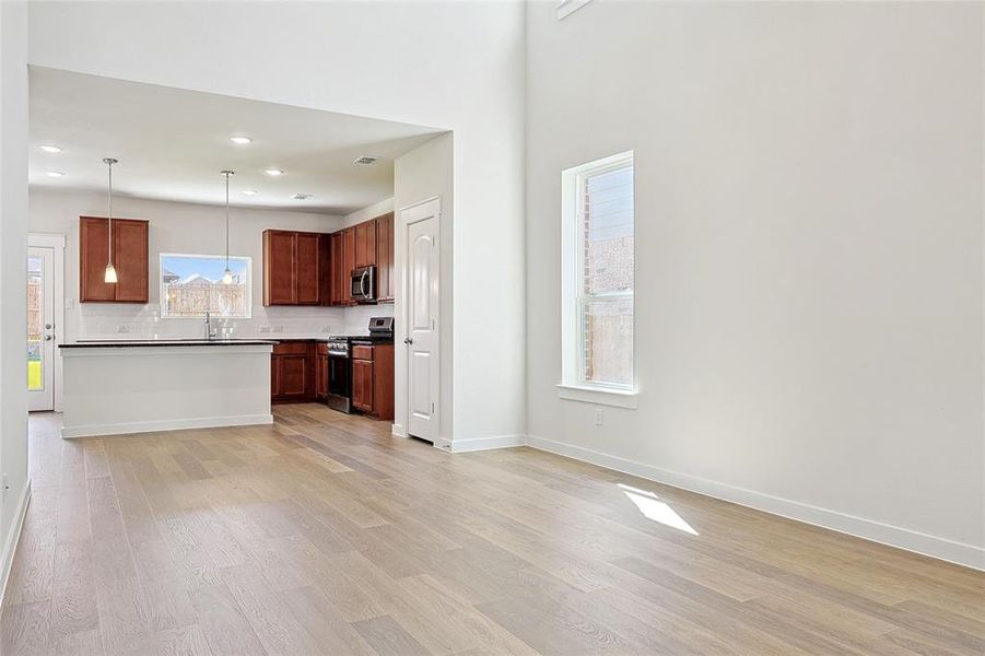 Kitchen featuring hanging light fixtures, sink, tasteful backsplash, appliances with stainless steel finishes, and light wood-type flooring