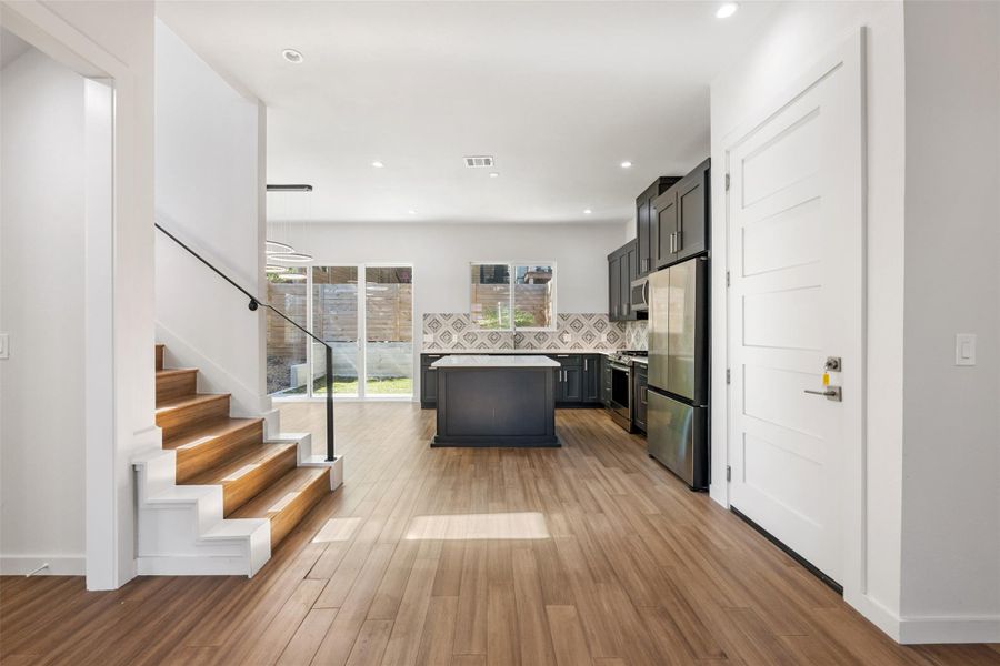 Kitchen featuring decorative backsplash, a kitchen island, stainless steel appliances, light wood-type flooring, and recessed lighting