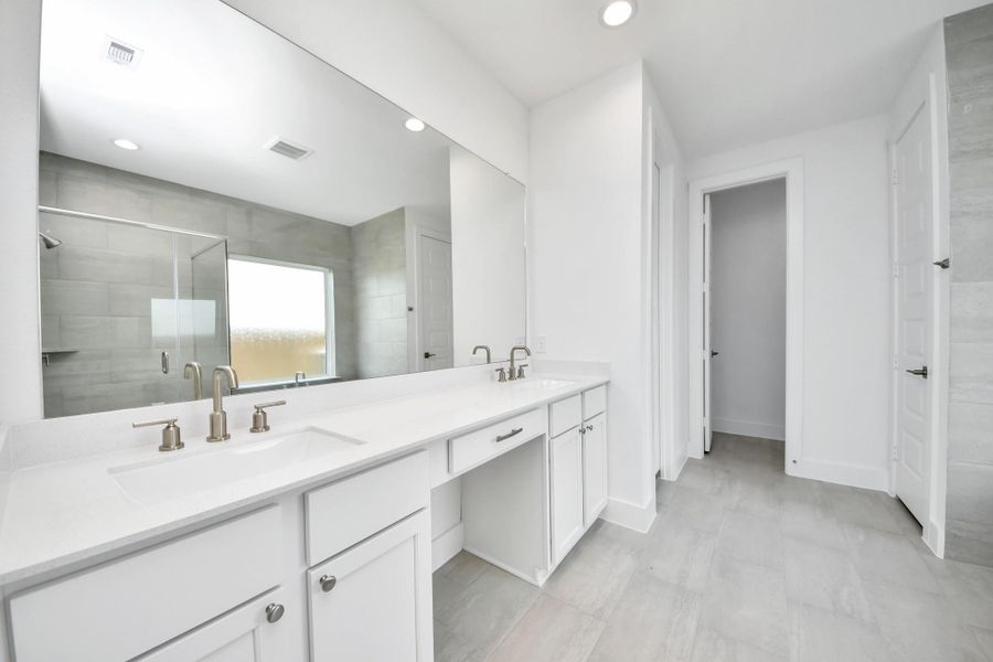 Escape to a spa-like oasis in this primary bathroom. Enjoy a walk-in shower with tile surround, a separate garden tub with custom detailing, and an elegant vanity featuring light countertops, modern hardware, and beautiful recessed lights. Experience luxury and relaxation in every detail.