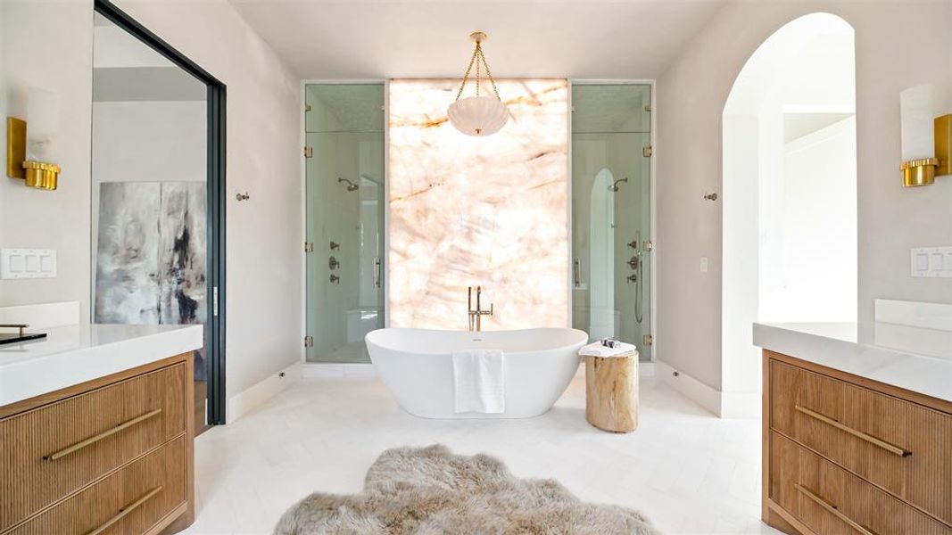 Grand bath framed with dual frameless glass doors to a massive walk-in shower.