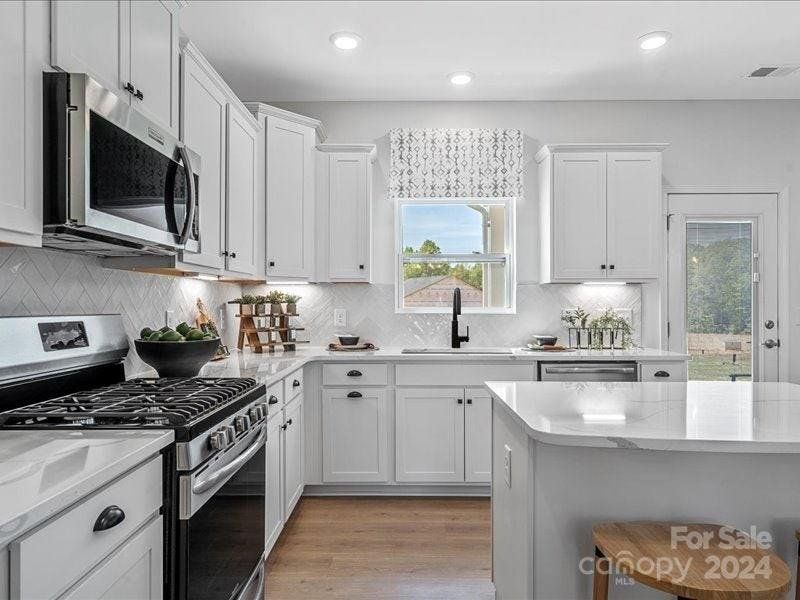 PHOTO REPRESENTATION ONLY. Kitchen of decorated model home. Finishes are different than shown. Refer to the interior design selections for finishes. Refrigerator not included.