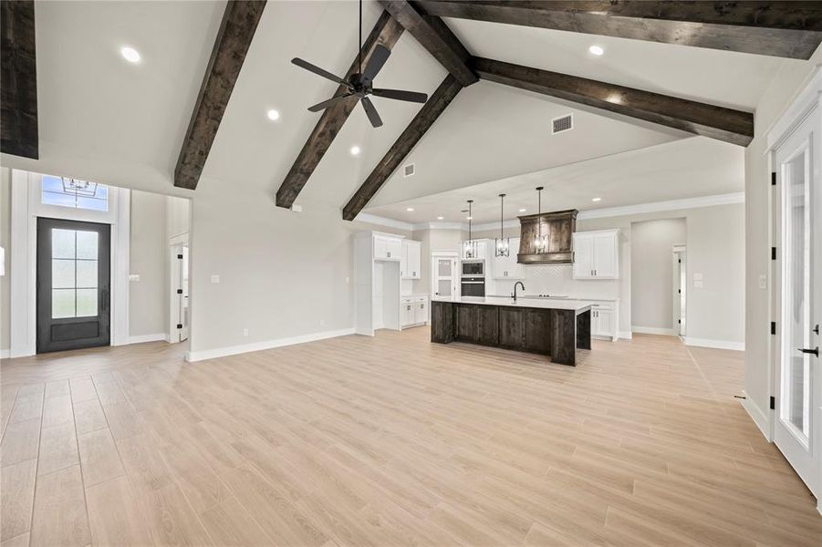 Unfurnished living room with light wood-style flooring, high vaulted ceiling, ceiling fan, recessed lighting, and beamed ceiling