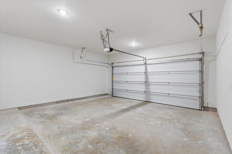 Clean two-car garage with bright recessed lighting, crisp white walls and an automatic overhead door.