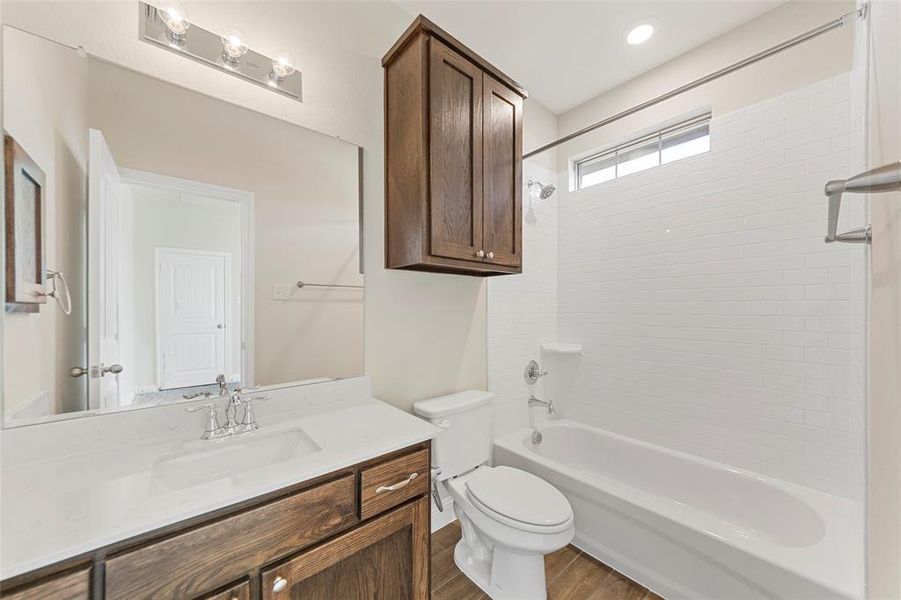 Full bathroom featuring hardwood / wood-style floors, vanity,  shower combination, and toilet