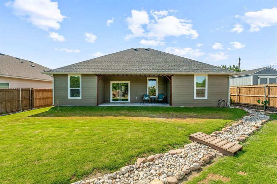 Back of house with a shingled roof, a patio area, and a fenced backyard