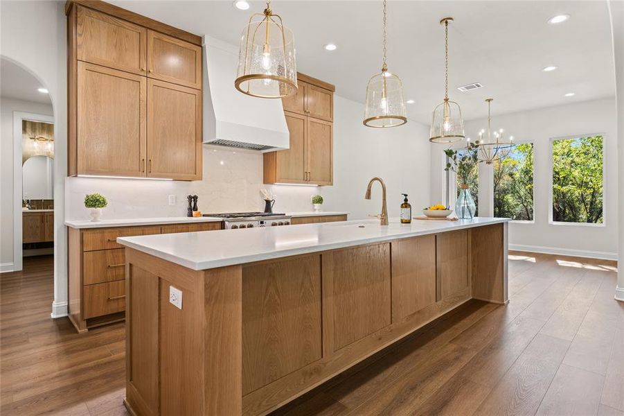 Kitchen featuring arched walkways, recessed lighting, dark wood finished floors, light stone countertops, and decorative light fixtures
