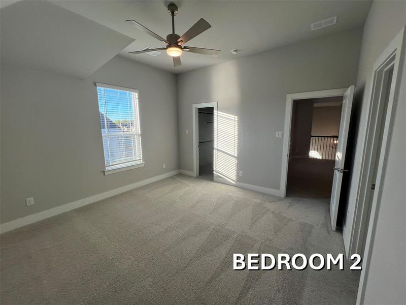 Carpeted room featuring a vaulted ceiling and a ceiling fan with integrated lighting Carpeted room featuring a vaulted ceiling and a ceiling fan with integrated lighting