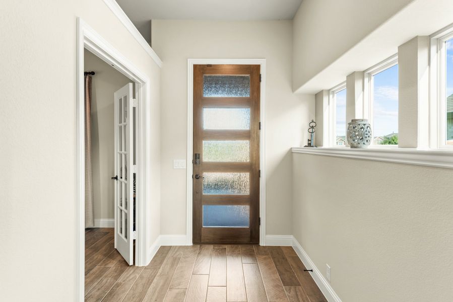 Entryway with wood front door with frosted glass panels, hardwood floors, and side windows letting in natural light