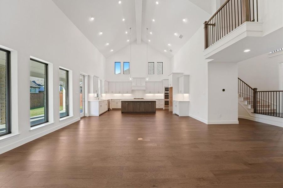 Unfurnished living room with dark wood-type flooring, high vaulted ceiling, beamed ceiling, and recessed lighting