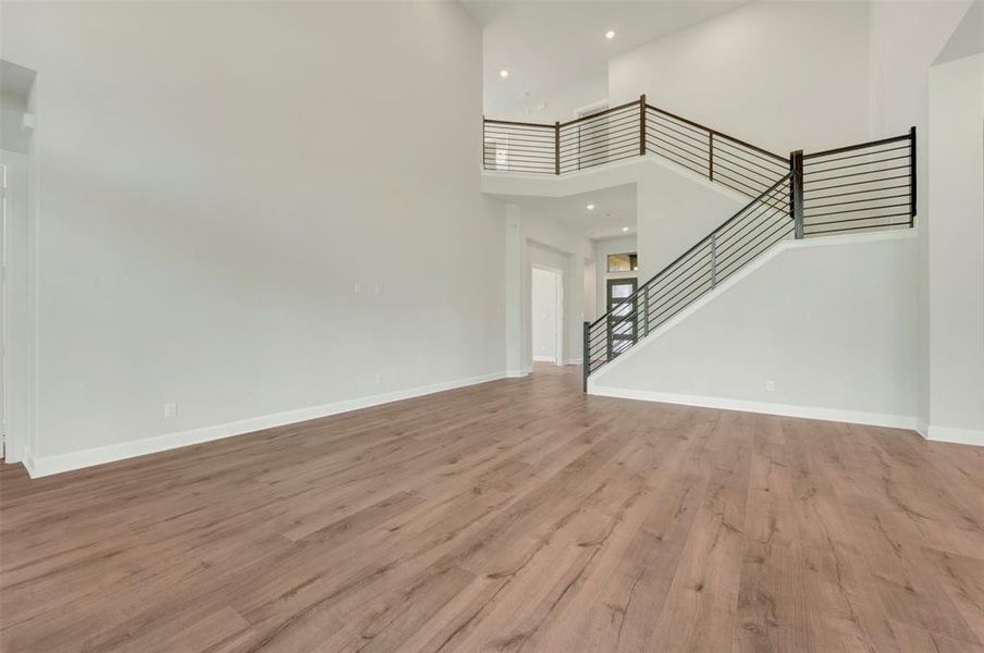 Unfurnished living room with light wood finished floors and a high ceiling