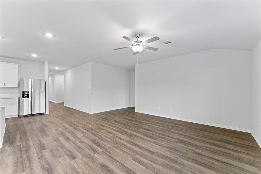 Unfurnished living room with a ceiling fan, recessed lighting, wood finished floors, and lofted ceiling Unfurnished living room with a ceiling fan, recessed lighting, wood finished floors, and lofted ceiling