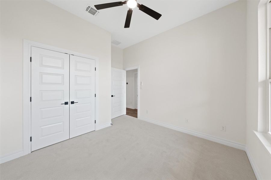 Unfurnished bedroom with carpet, ceiling fan, and a closet Unfurnished bedroom with carpet, ceiling fan, and a closet