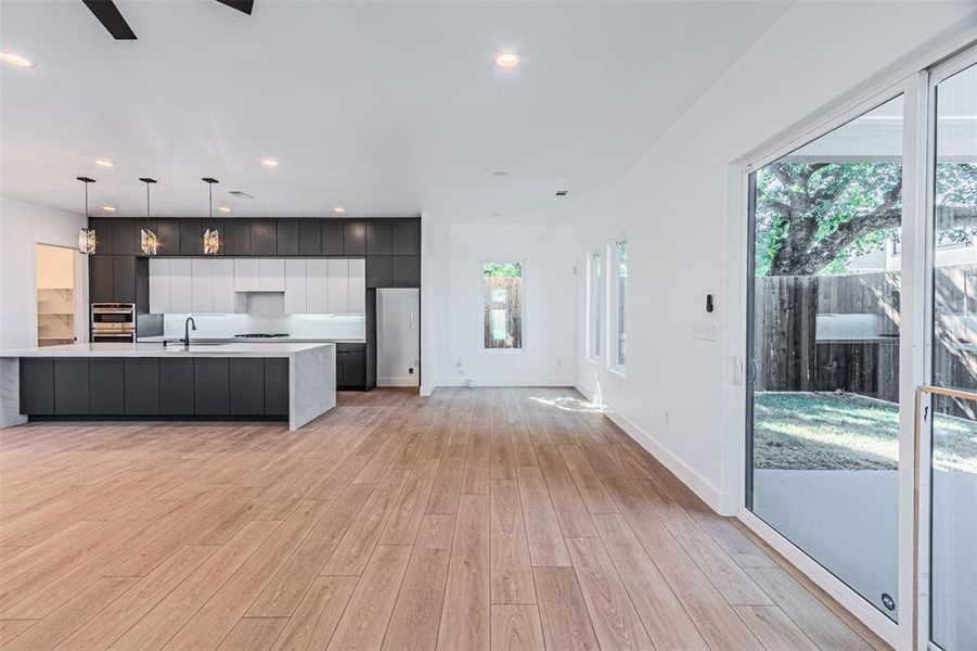 Kitchen with modern cabinets, open floor plan, hanging light fixtures, a kitchen island with sink, and light wood-style flooring