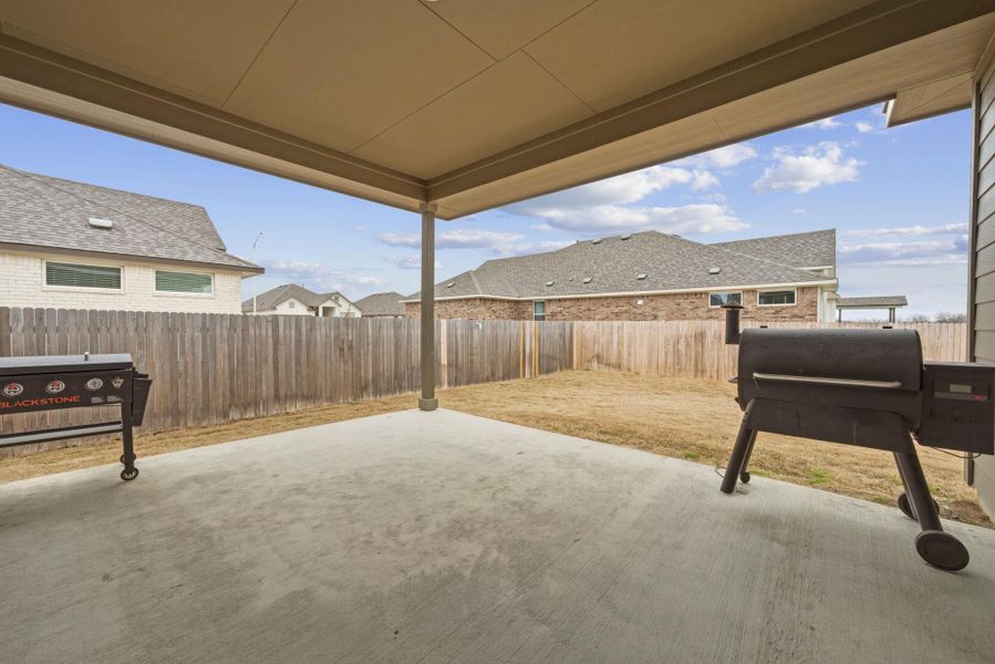 Fenced backyard featuring a patio, a grill, and a residential view