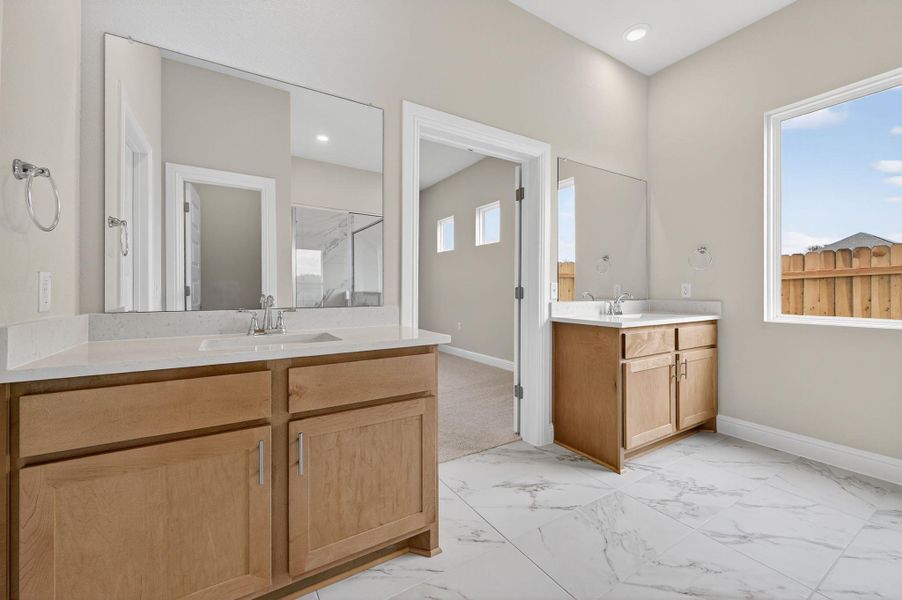 Bathroom with light marble finish flooring, two vanities, recessed lighting, and a marble finish shower