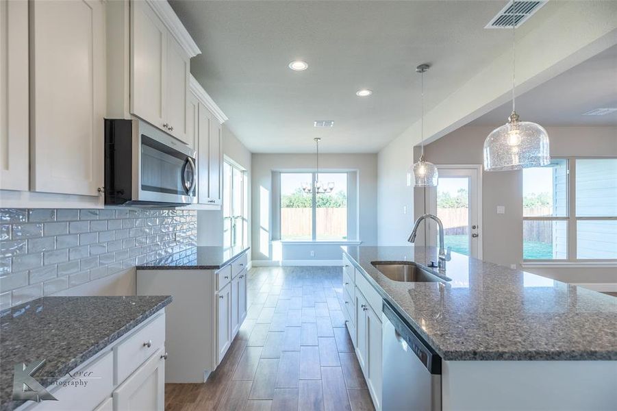 Kitchen with white cabinetry, appliances with stainless steel finishes, hanging light fixtures, recessed lighting, and dark stone counters