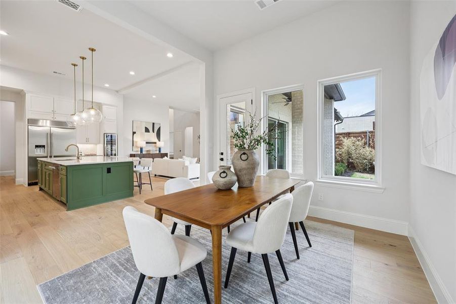 Dining room featuring light wood-type flooring, healthy amount of natural light, recessed lighting, and wine cooler