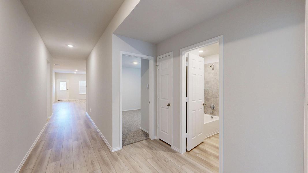 A well-lit corridor guides residents to private spaces, including a pristine full bathroom.