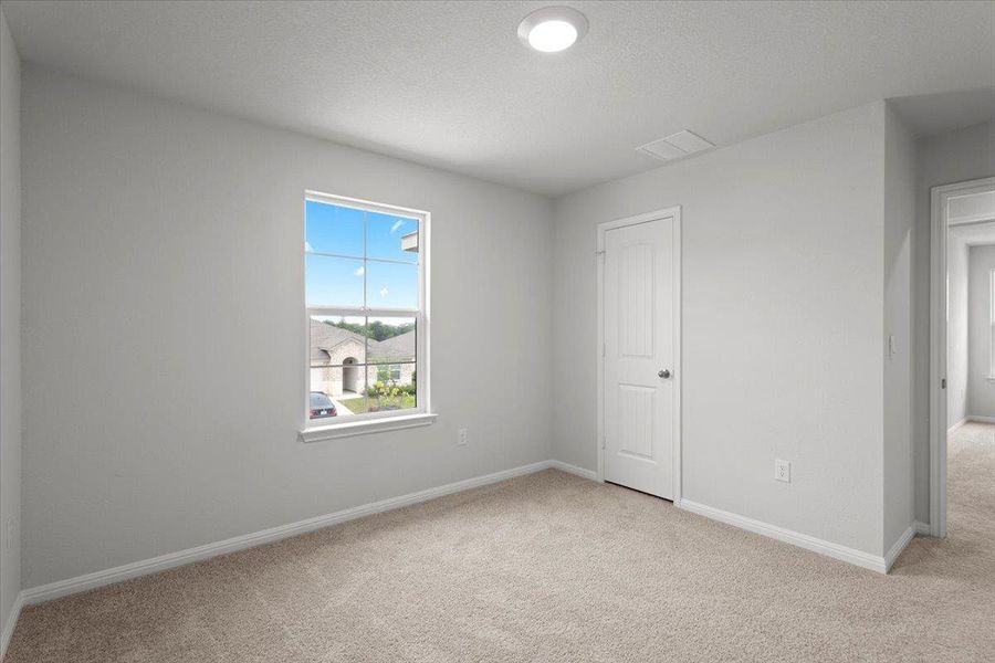 Neutral-toned room featuring a single window with grids, light beige carpeting, white baseboards, and a white paneled door