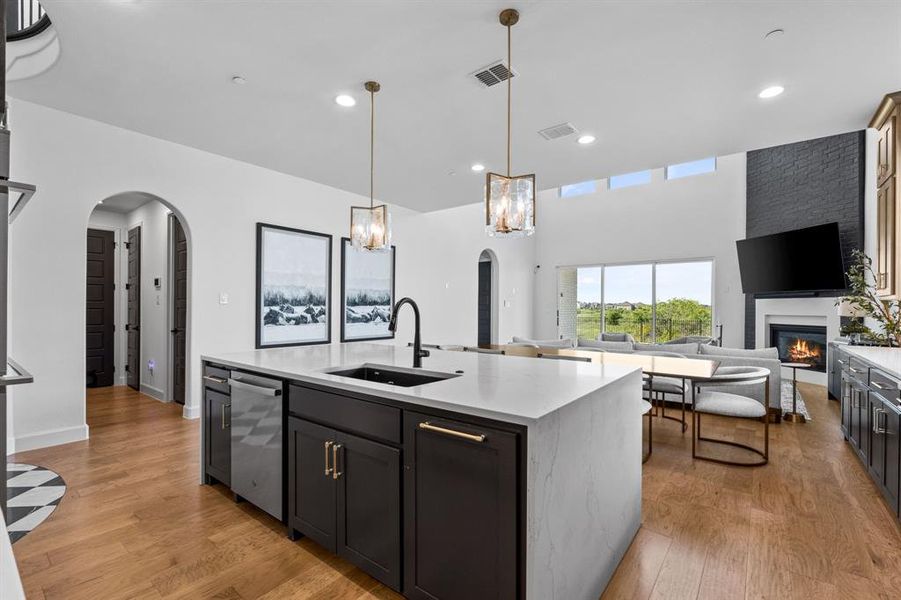 Kitchen with arched walkways, light stone countertops, open floor plan, a glass covered fireplace, and recessed lighting Kitchen with arched walkways, light stone countertops, open floor plan, a glass covered fireplace, and recessed lighting