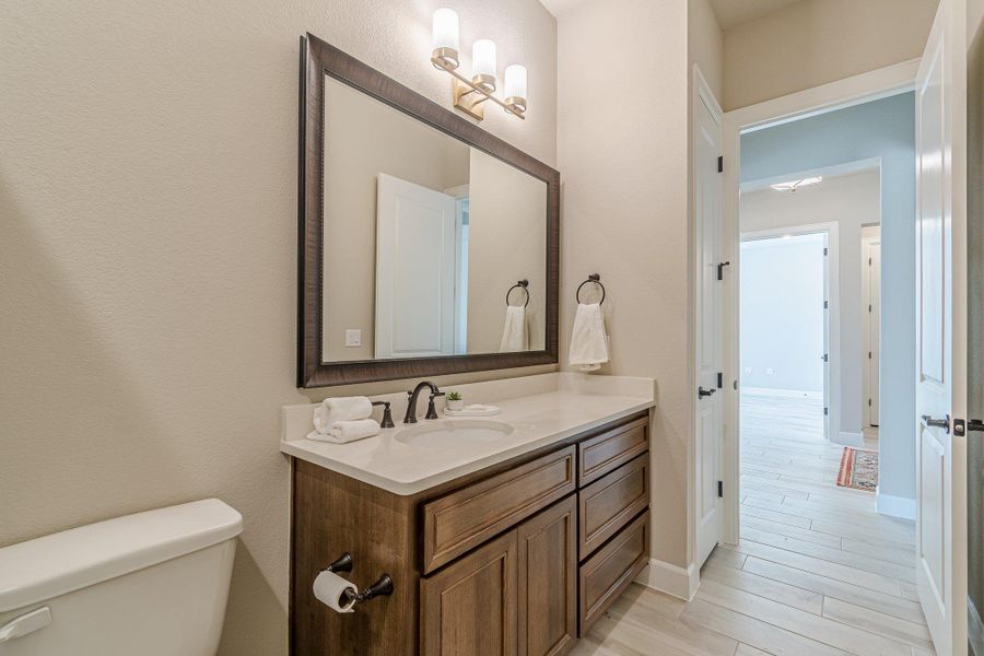 Half bathroom with toilet, baseboards, wood finished floors, and vanity