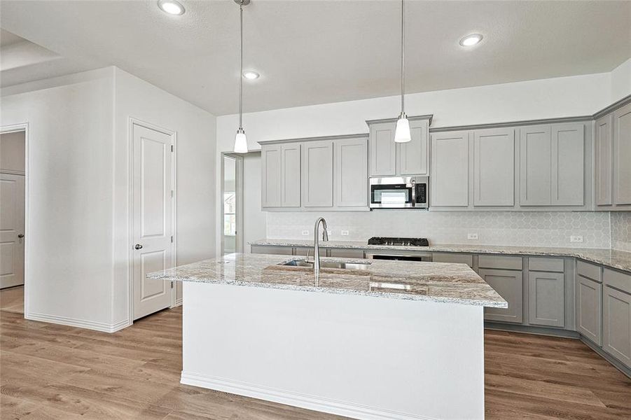 Kitchen with hardwood / wood-style floors, sink, an island with sink, and stainless steel appliances