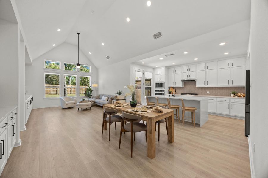 Dining room with a high ceiling, light wood-style floors, a ceiling fan, and recessed lighting