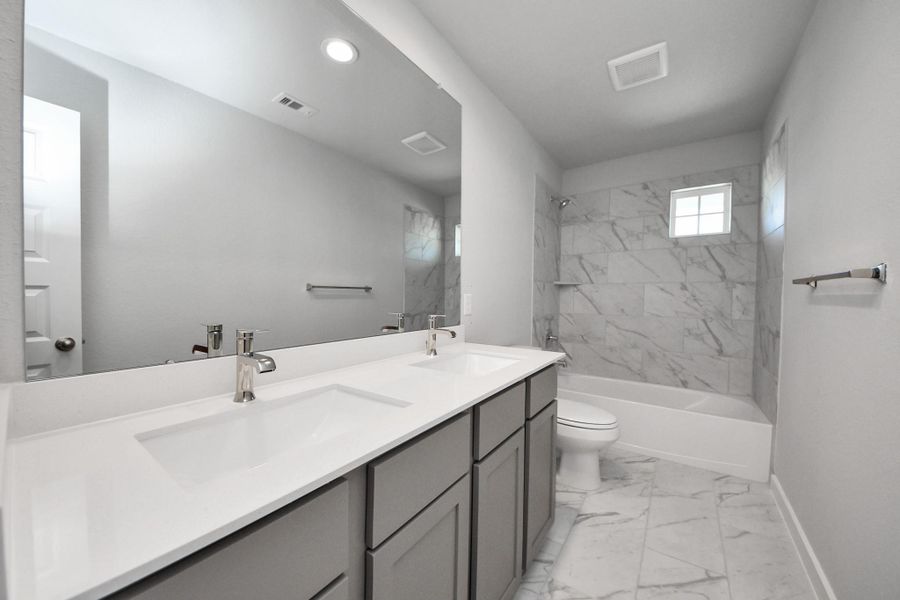 Secondary bath features tile flooring, bath/shower combo with tile surround, light stained wood cabinets, beautiful light countertop. Secondary bath features tile flooring, bath/shower combo with tile surround, light stained wood cabinets, beautiful light countertop.