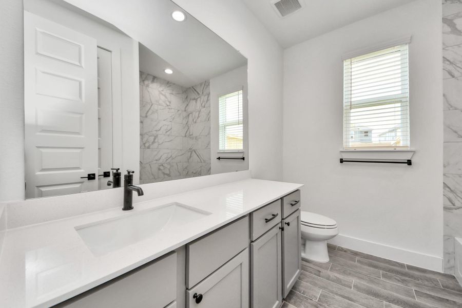 Secondary bath features tile flooring, bath/shower combo with tile surround, light stained wood cabinets, beautiful light countertop. Secondary bath features tile flooring, bath/shower combo with tile surround, light stained wood cabinets, beautiful light countertop.