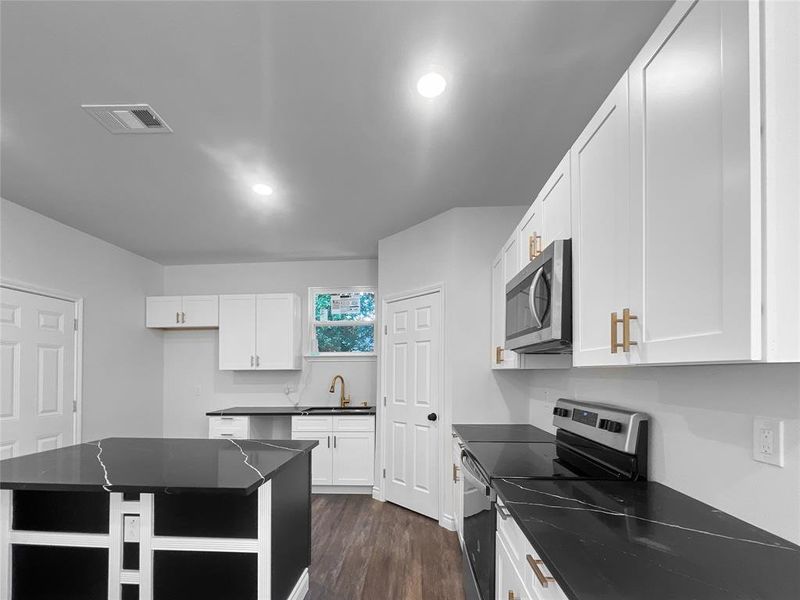 Kitchen featuring white cabinets, a center island, appliances with stainless steel finishes, dark hardwood / wood-style flooring, and sink