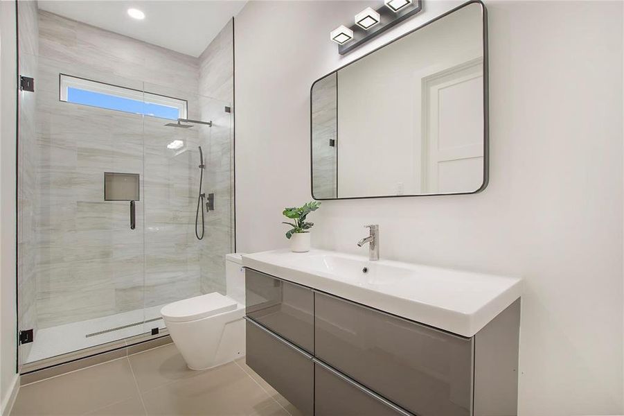 Bathroom with toilet, a shower with shower door, vanity, and tile patterned floors