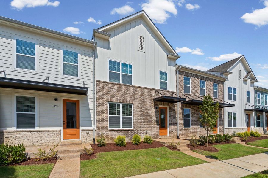 Modern townhome community featuring contemporary architectural design with mixed brick and fiber cement siding exteriors, multi-pane windows, and coordinated orange accent doors