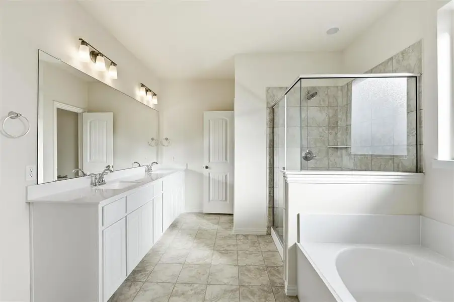 Bathroom featuring a garden tub, double vanity, and a shower stall