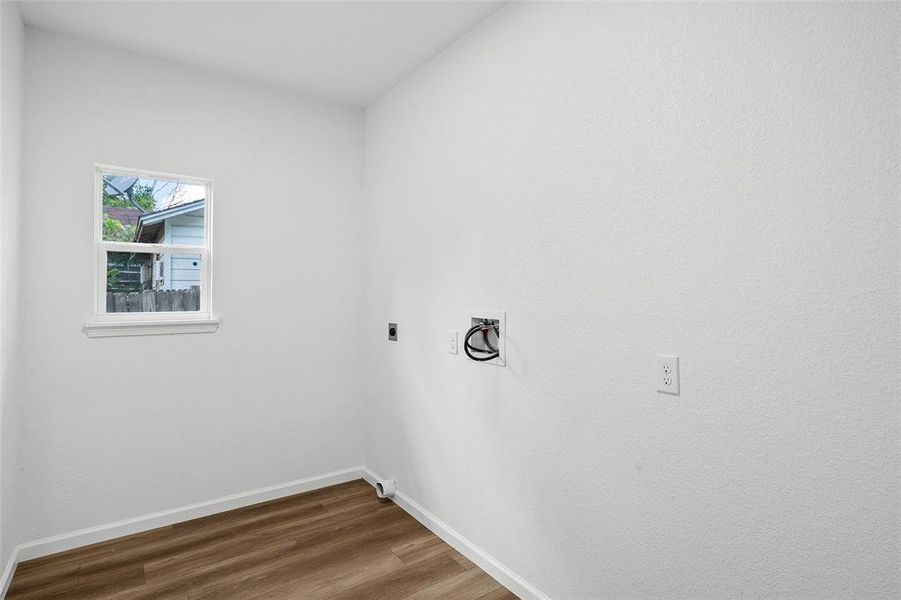 Dedicated utility space featuring wood-finish flooring, a single window, and a white baseboard trim Dedicated utility space featuring wood-finish flooring, a single window, and a white baseboard trim