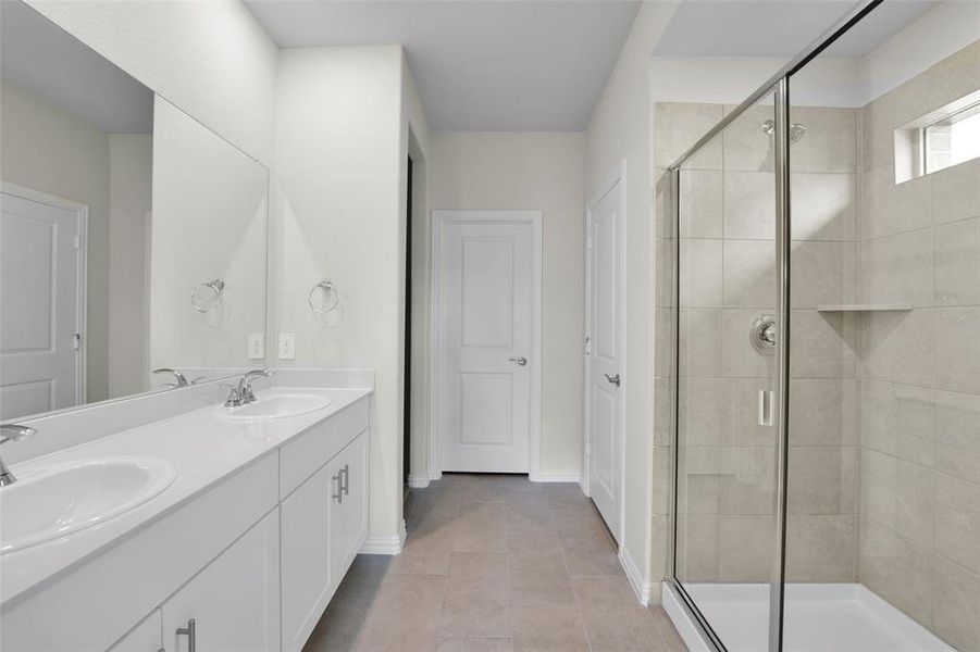 Full bathroom featuring a stall shower, double vanity, and light tile patterned floors Full bathroom featuring a stall shower, double vanity, and light tile patterned floors