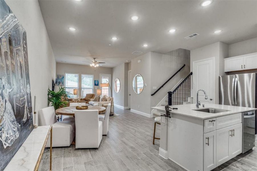 Kitchen featuring light hardwood / wood-style floors, white cabinetry, a center island with sink, sink, and ceiling fan