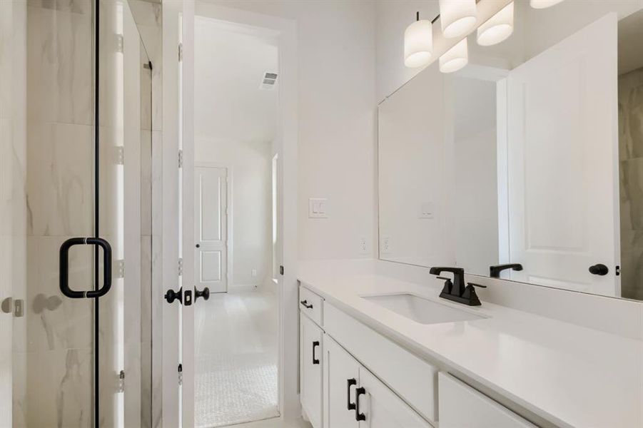 Contemporary bathroom featuring a spacious vanity with an undermount sink, a large mirror, and matte black hardware Contemporary bathroom featuring a spacious vanity with an undermount sink, a large mirror, and matte black hardware