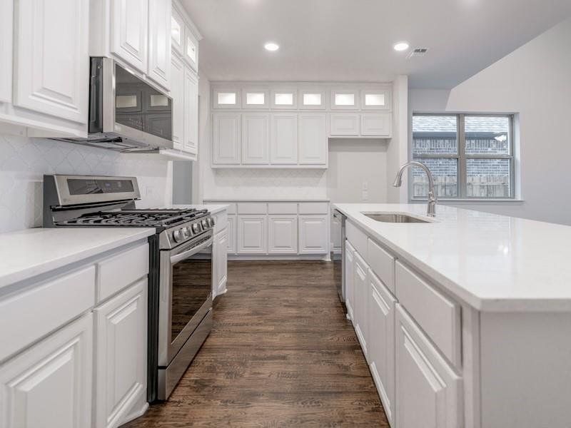 Kitchen featuring sink, tasteful backsplash, appliances with stainless steel finishes, dark hardwood / wood-style floors, and white cabinets