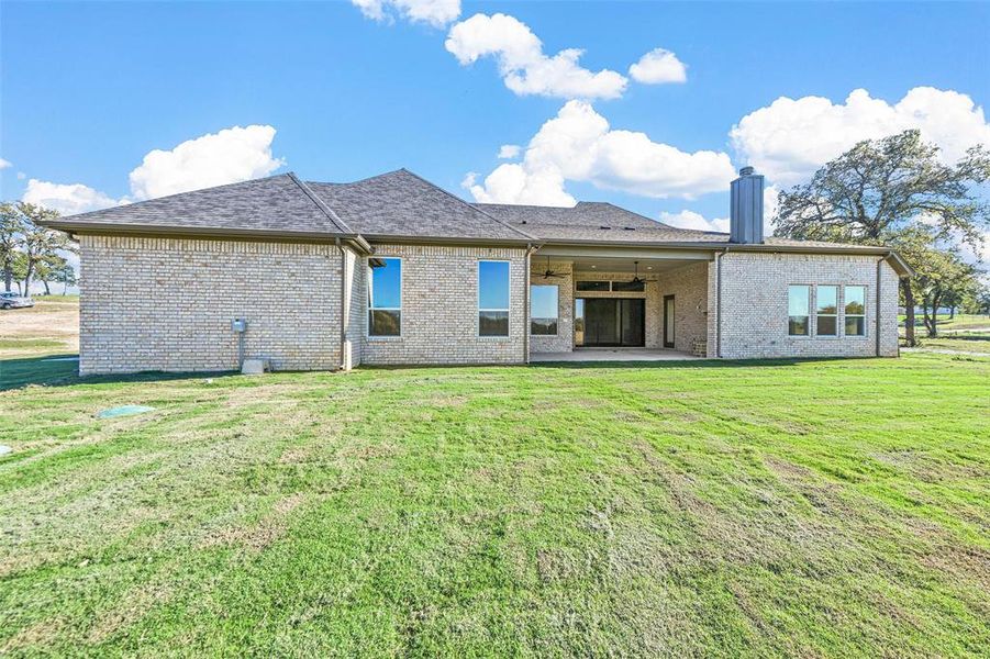 Rear view of property featuring ceiling fan, a yard, and a patio