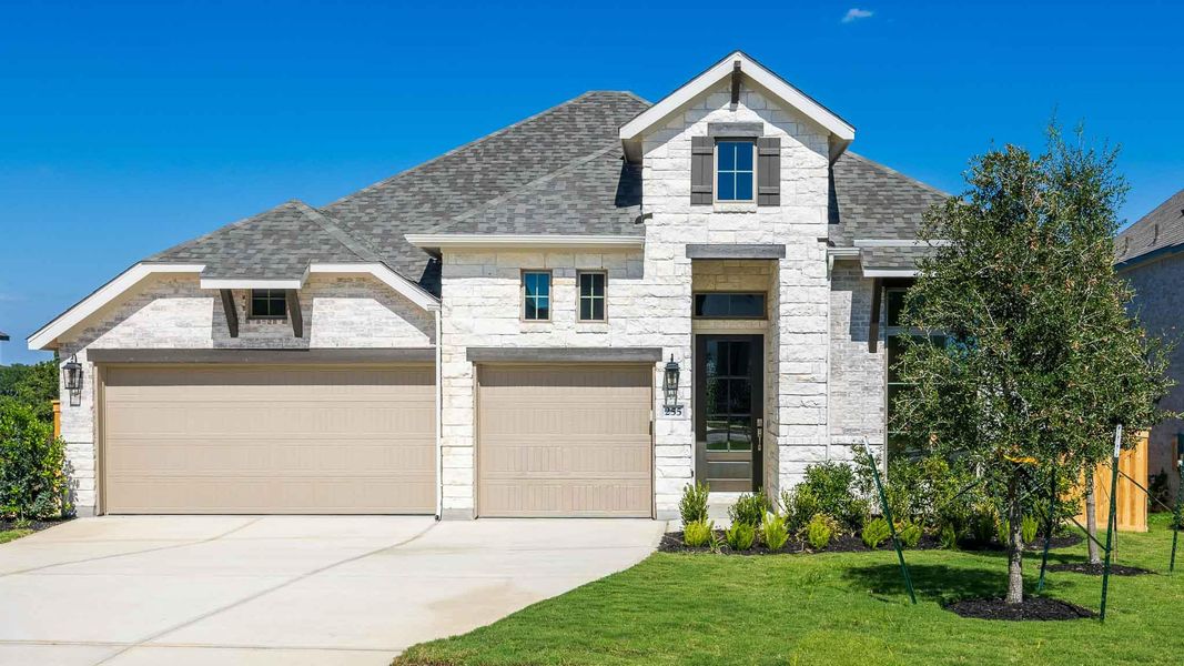 French country home featuring roof with shingles, stone siding, driveway, and a front yard