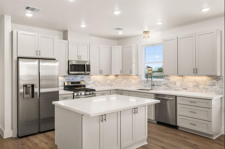 The kitchen offers 42" cabinetry, quartz countertops, large island, tile backsplash, walk-in pantry, and a full appliance package including gas cooktop and built-in oven